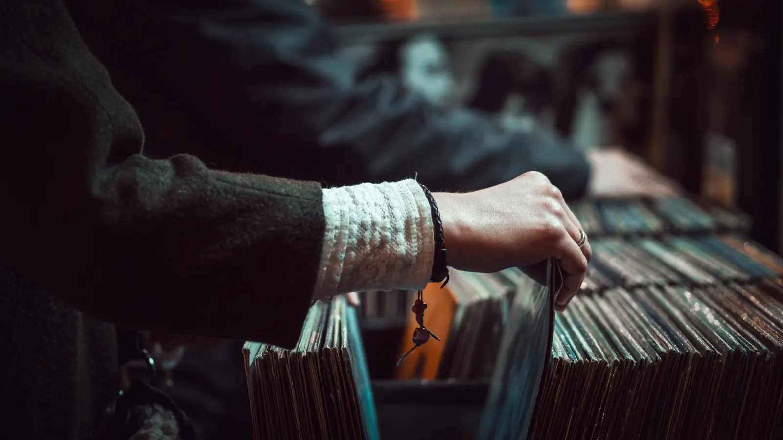 A hand browsing vinyl records in record-shop bins