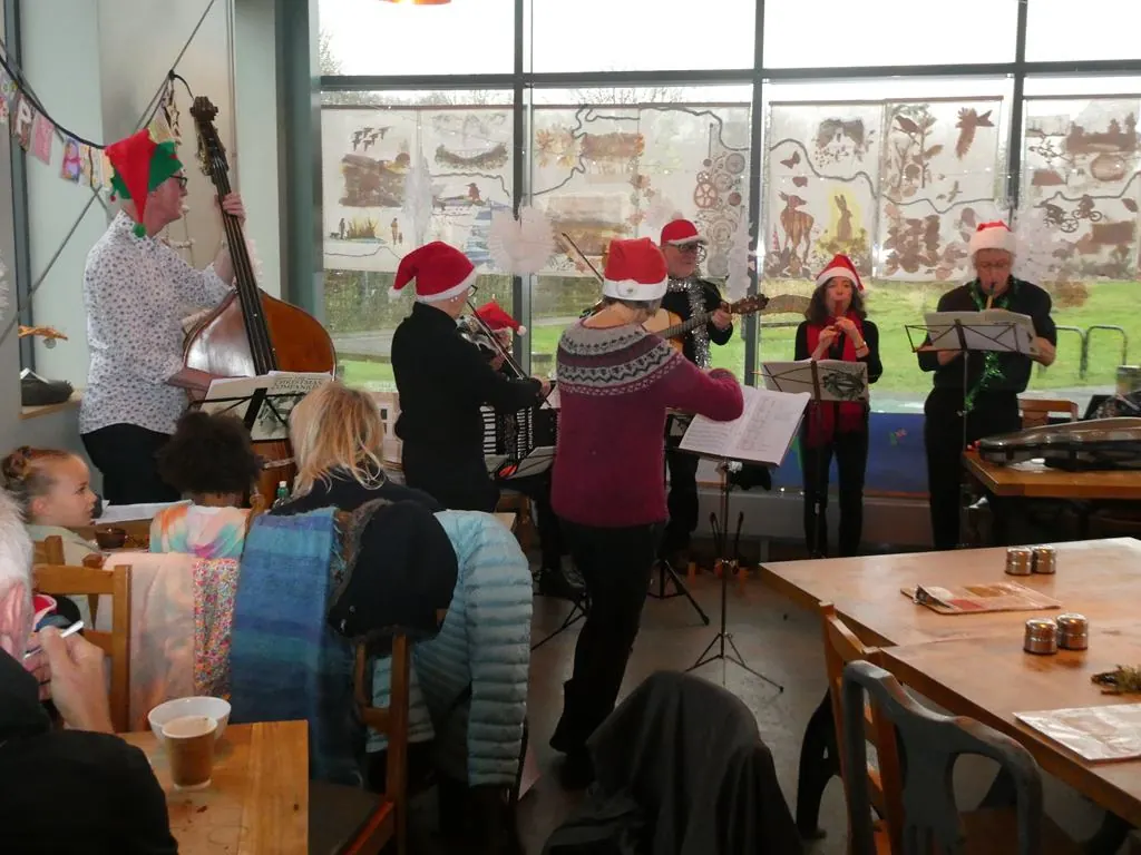 Musicians in festive hats performing Christmas music indoors