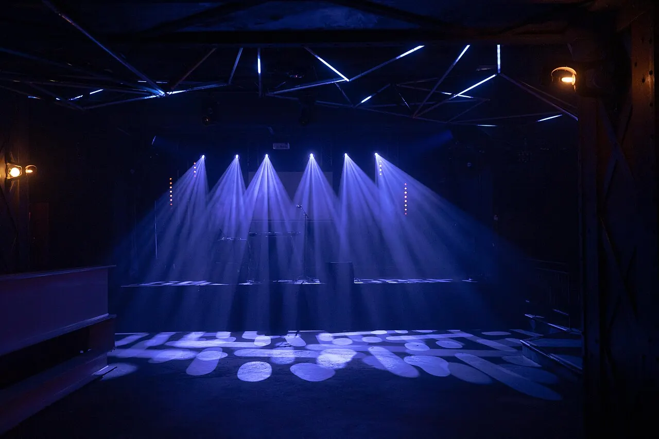 Empty concert stage with blue lights and a microphone stand