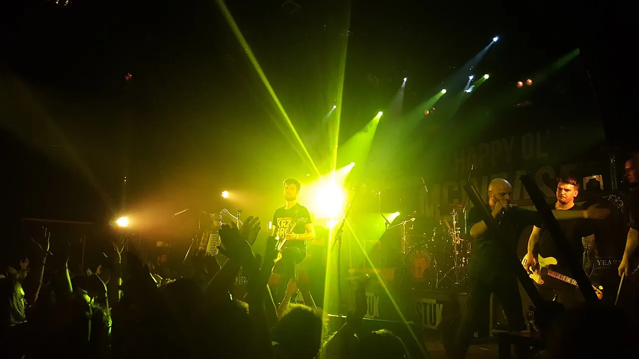 Musicians performing under green stage lights at a concert