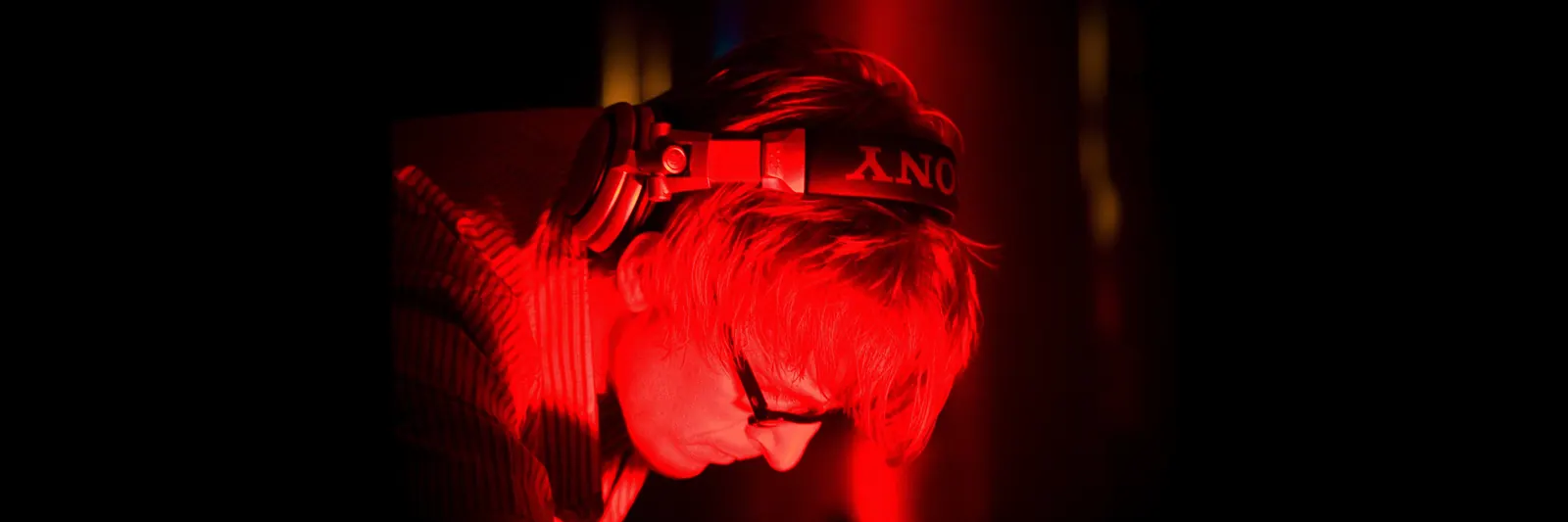 A headphone-wearing performer in red light in an archival Simian Mobile Disco photograph