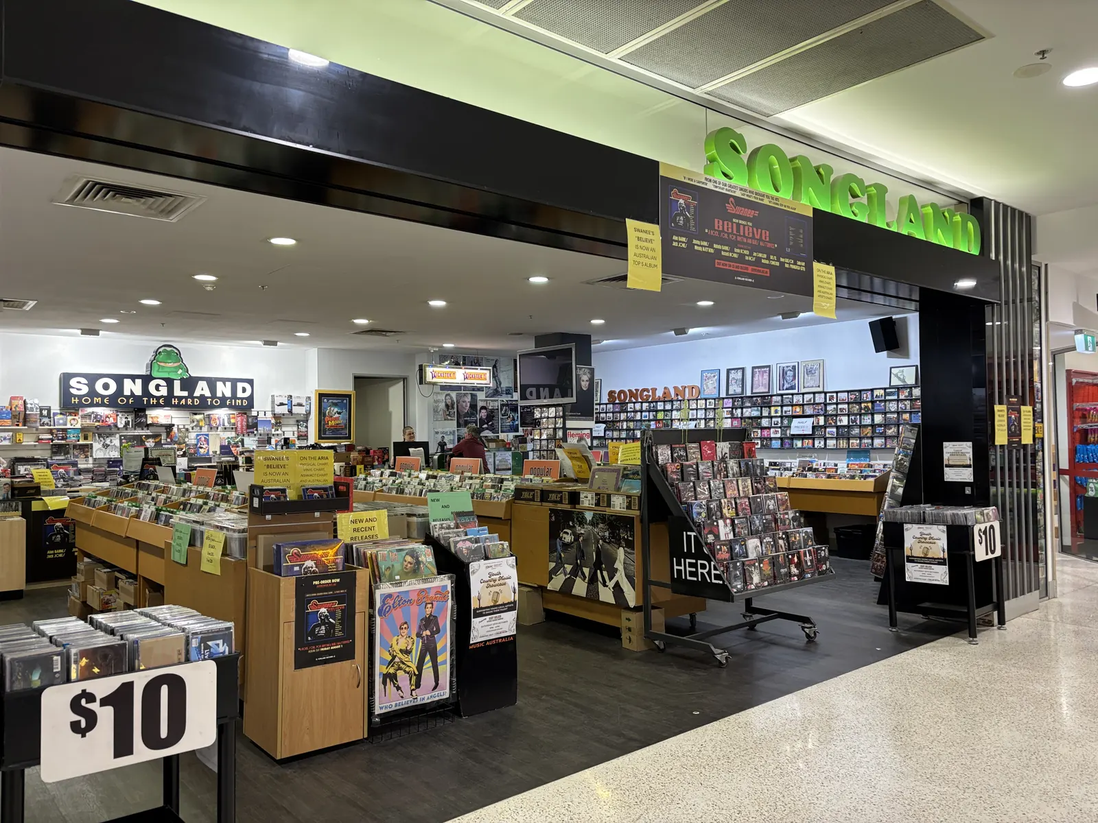 Open record-shop entrance with green Songland lettering above rows of records and CDs